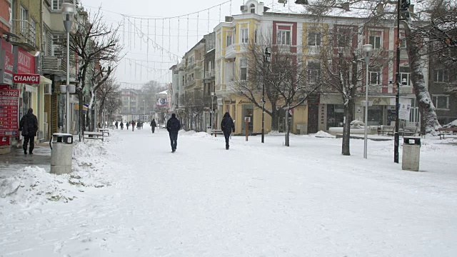 在一个严酷的冬日里，人们走在被雪覆盖的街道上视频素材