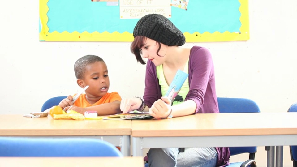 在英国，一名学生在教室里给蹒跚学步的孩子朗读。视频素材