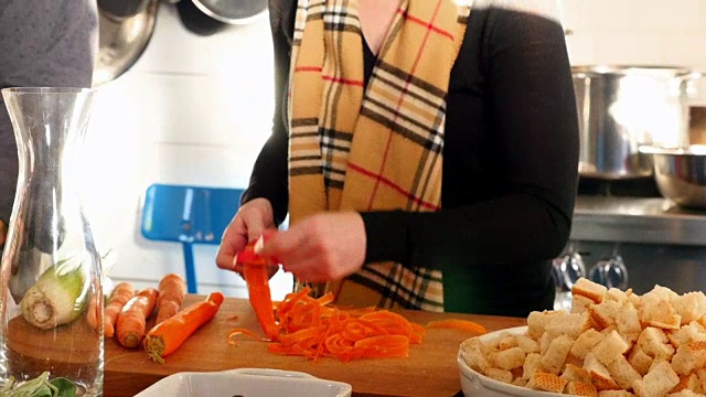 一名妇女在烹饪课上和朋友剥有机胡萝卜视频素材