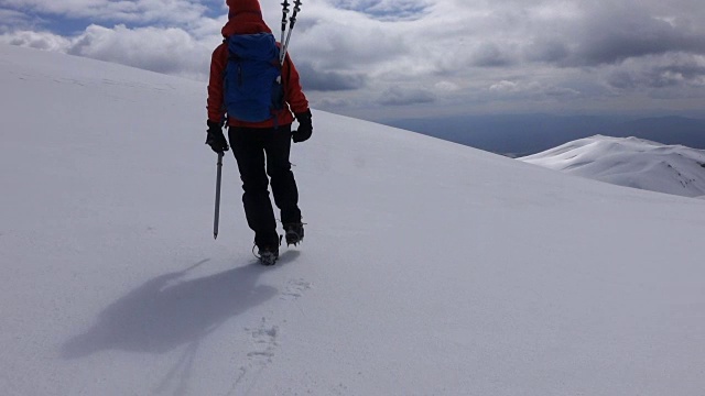 一位女攀登者正在一座山峰的顶峰上行走视频下载