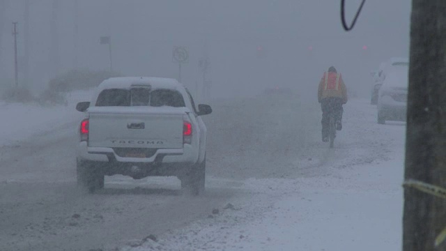 一个男人在暴风雪中骑着他的自行车，暴风雪，东北视频素材