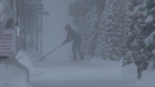 在暴风雪条件下铲雪的人，白湖效应暴风雪视频素材