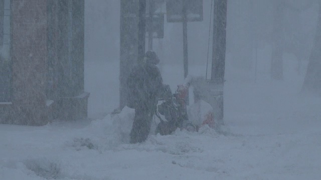 在极端暴风雪条件下，强风中使用吹雪机的人视频素材