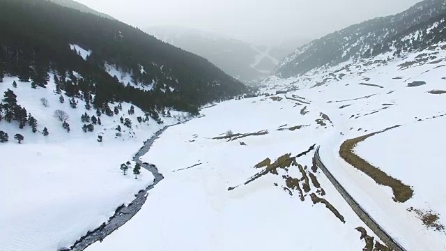 无人机拍摄的航拍镜头拍摄了美丽的安道尔雪景，与蜿蜒的河流在雪谷中流淌形成了很好的对比。视频素材