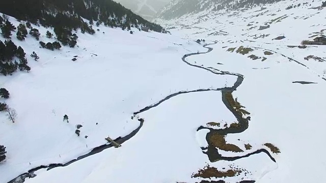 无人机拍摄的航拍镜头拍摄了美丽的安道尔雪景，与蜿蜒的河流在雪谷中流淌形成了很好的对比。视频素材