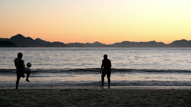 两名巴西男子在海浪撞击科帕卡巴纳海滩的慢镜头中来回排球视频素材