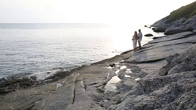 一对夫妇沿着海岸线上的岩石散步，眺望大海视频素材