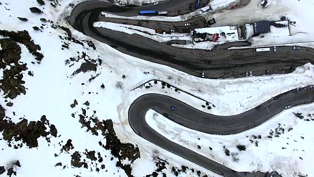 无人机在比利牛斯山脉上空拍摄的航拍镜头，上面有雪景和美丽的曲线，汽车在比利牛斯山脉上行驶。4 k UHD。视频素材