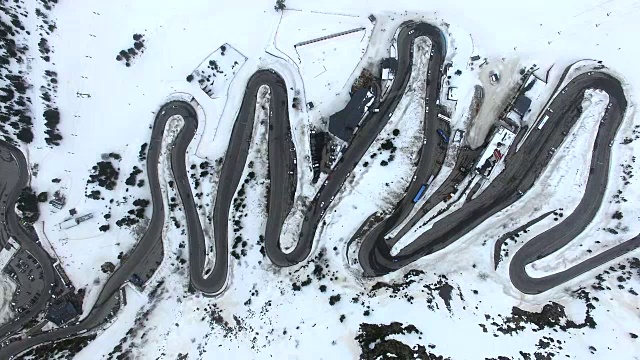 无人机在比利牛斯山脉上空拍摄的航拍镜头，上面有雪景和美丽的曲线，汽车在比利牛斯山脉上行驶。4 k UHD。视频素材