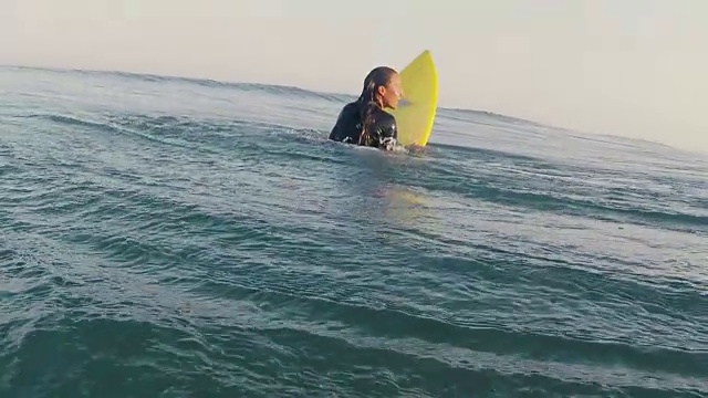 在法国南部大西洋海岸荒芜的沙滩上，美丽的女性冲浪者在海浪中划着冲浪板。视频素材