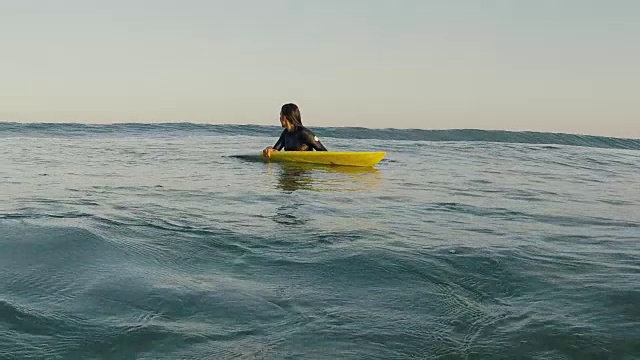 美丽的女性冲浪者在水与冲浪板看海浪翻滚在废弃的沙滩在法国南部大西洋海岸。视频素材