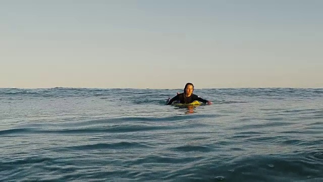 女性冲浪者在日落时在海上划桨在大西洋海岸在法国南部的沙漠海滩。视频素材