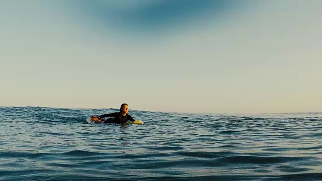 美丽的女性冲浪者在日落在荒凉的沙滩上划水在大西洋海岸在法国南部。视频素材