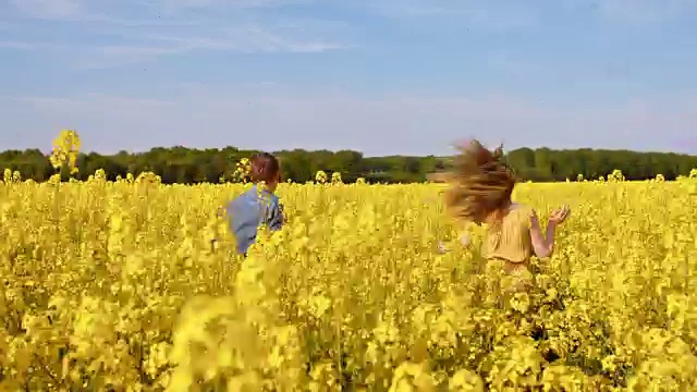 一对幸福的夫妇在油菜花盛开的田地里视频素材