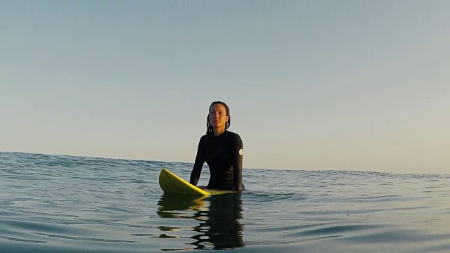 在法国南部大西洋海岸荒芜的沙滩上，女冲浪者坐在冲浪板上等待海浪。视频素材