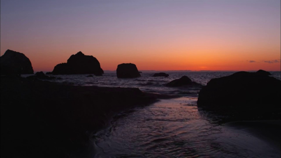 橙色天空下，海浪拍打着夏威夷海岸。视频素材