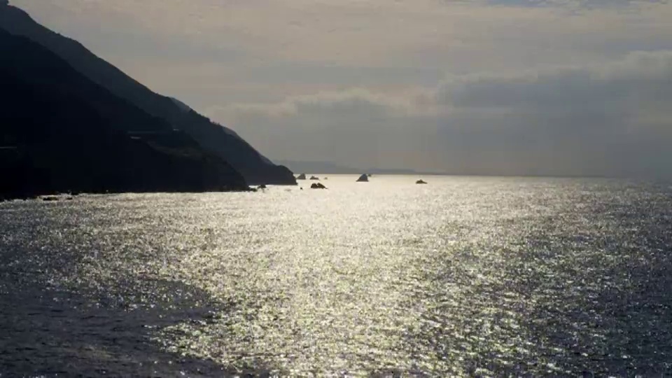 宽阔的山脉在海岸波光粼粼的海洋在下午晚些时候视频素材