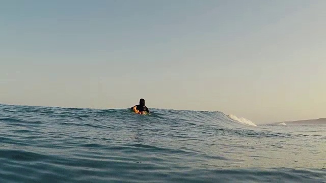 在法国南部大西洋海岸荒芜的沙滩上冲浪的女性冲浪者划着冲浪板越过海浪。视频素材