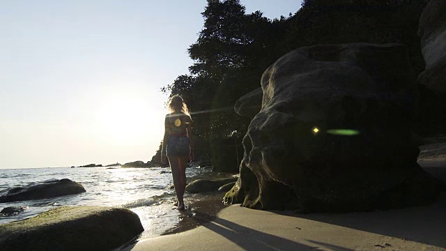 年轻女子沿着海滩走向海边视频素材