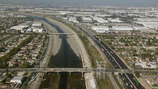 航空拍摄的洛杉矶河流经水泥堤岸沿着长滩高速公路，或I-710。视频素材