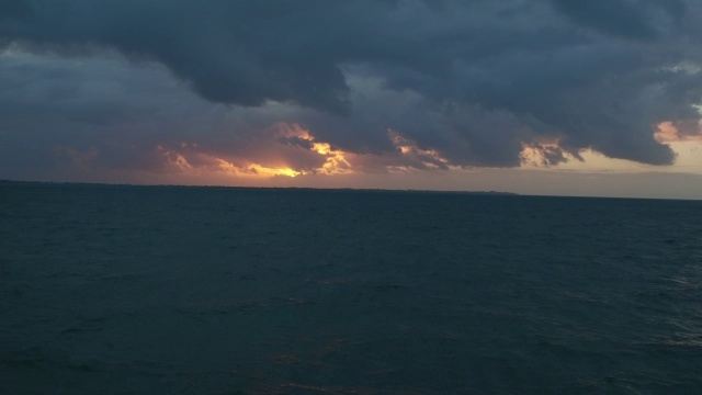 空中漂浮在坎昆黑暗的海洋上，朝着隐藏在乌云后面的夕阳视频素材