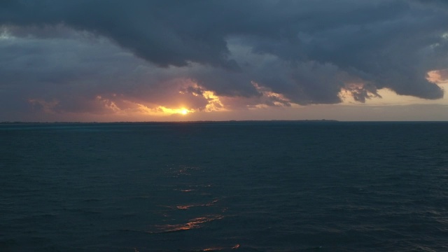 空中漂浮在坎昆黑暗的海洋上，夕阳在水面上投下金色的微光视频素材