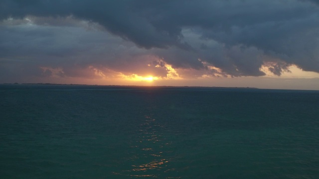 空中拉远在坎昆黑暗的海洋，夕阳在水面上投下金色的微光视频素材