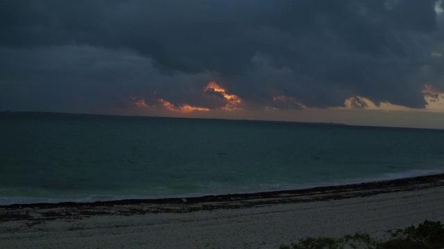 空中翱翔在海滩上，朝着大海上熊熊升起的日出视频素材