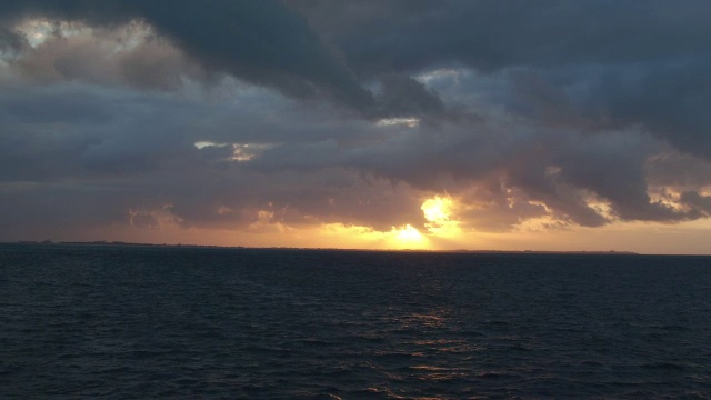 空中朝着坎昆波光粼粼的海面上金色的夕阳移动视频素材