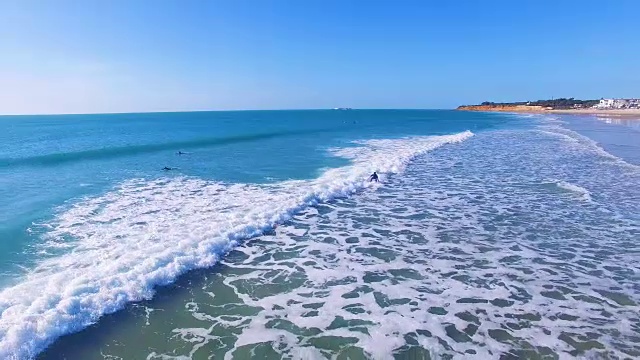 冲浪者的鸟瞰图在一个惊人的和未被破坏的海滩在西班牙海岸视频素材