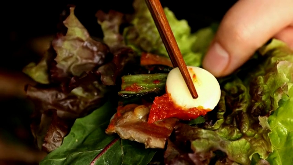 用生菜叶包裹猪腹肉，配上芥末泡菜(韩国流行的传统配菜)和大蒜视频素材