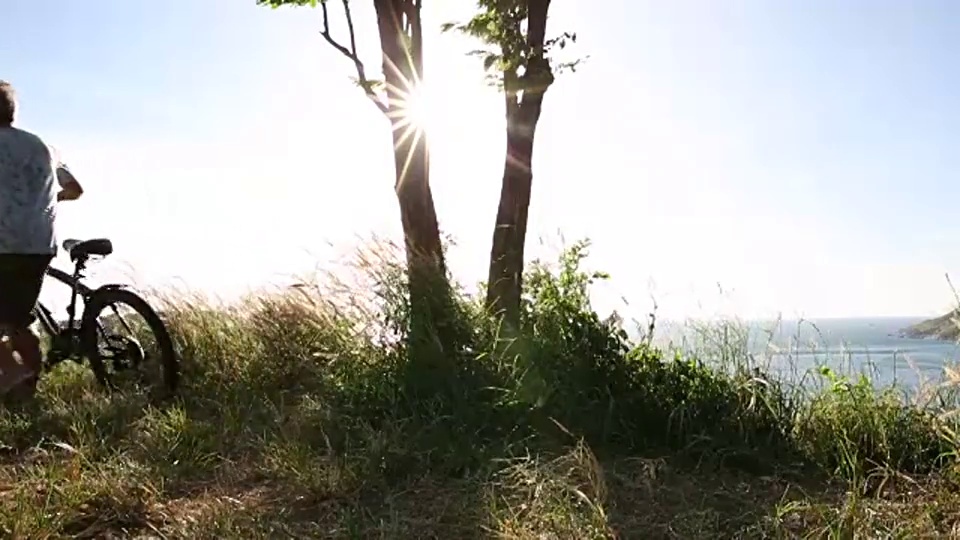 一名男子骑着自行车停在远处，眺望大海视频素材