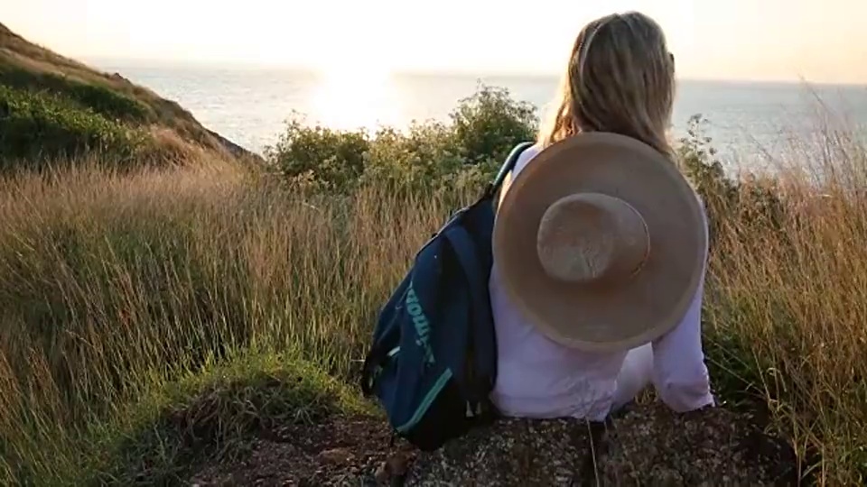 一个女人在山间徒步旅行，眺望大海视频素材