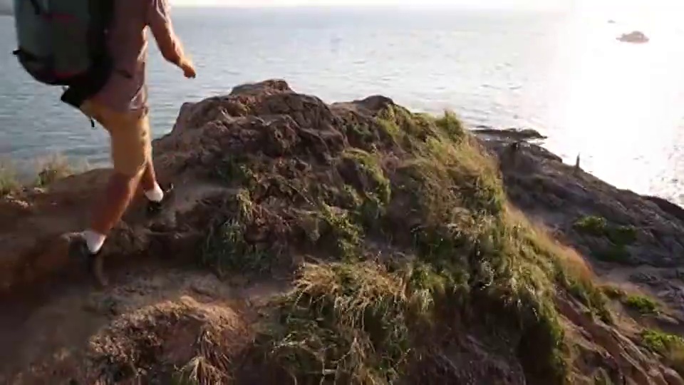 一名男性徒步旅行者越过山脊，眺望大海视频素材