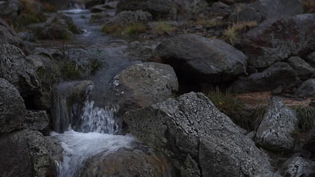 特写，静态镜头的浓烟滚滚的小溪，因为它落在崎岖的石头在冰岛南部。视频素材