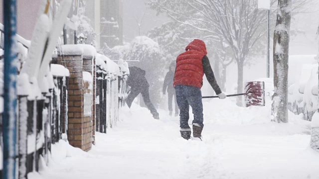 在纽约布鲁克林的一场暴风雪中，一个面目全非的男子在铲雪——慢动作视频素材