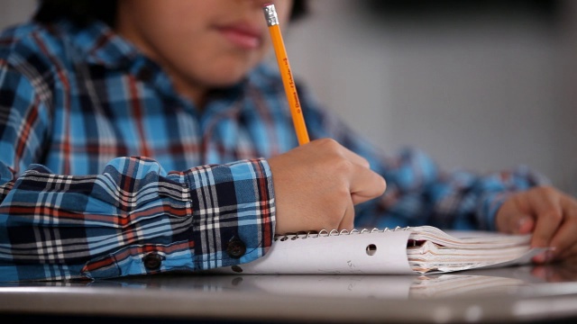 男学生在空教室的书桌上写字视频素材