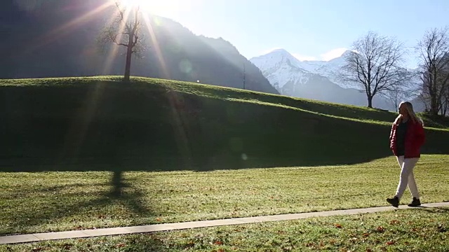 一个女人走在草地上的小路上，望向群山视频素材