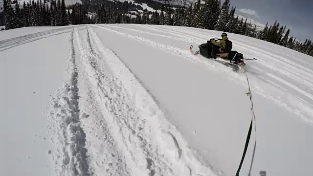 在蒙大拿州的群山中，一个面目全非的真人被拖在一辆雪地摩托后面视频素材