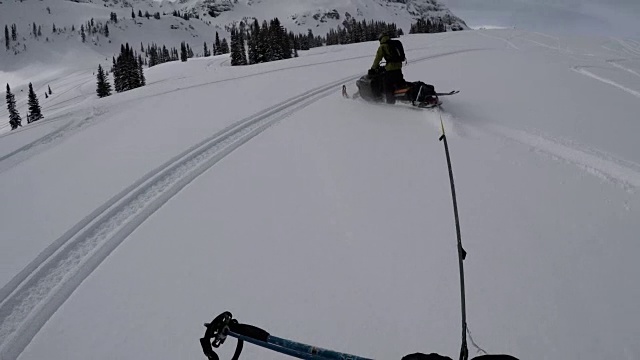 外面很冷——在落基山脉的边远地区，一个认不出的真实的人被一辆雪地摩托拖着走——4k视频素材