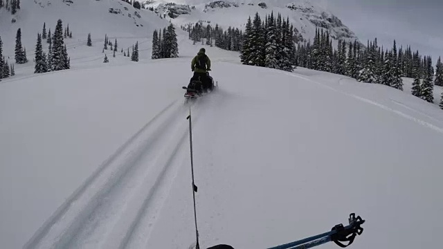 外面很冷——在落基山脉的边远地区，一个认不出的真实的人被一辆雪地摩托拖着走——4k视频素材