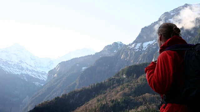 一个登山者在黎明时爬上斜坡，望向群山视频素材