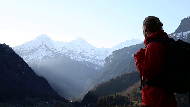 一个登山者在黎明时爬上斜坡，望向群山视频素材