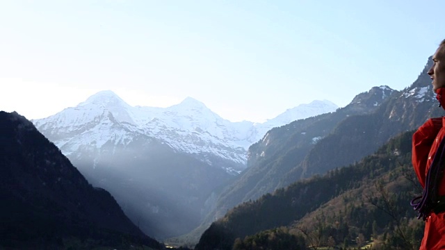 一个登山者在黎明时爬上斜坡，望向群山视频素材