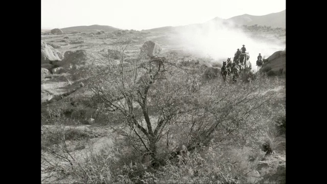 潘曼驾着马车，在沙漠的土路上骑马，背景是高山/美国视频素材