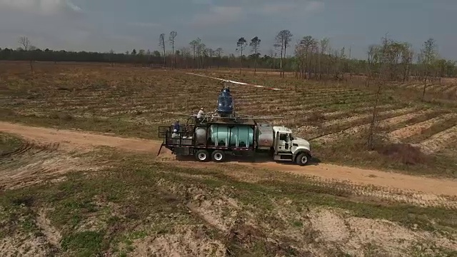 围绕直升机低空与树木飞行-无人机空中4K空中拍摄特技直升机喷洒农药和杀虫剂到作物和树木上，用于生产各种需要4K的农业运输视频素材