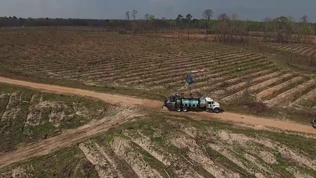 跟踪一架直升机在卡车上着陆-无人机空中4K空中拍摄特技直升机喷洒农药和杀虫剂在作物和树木上生产各种需要4K运输视频素材