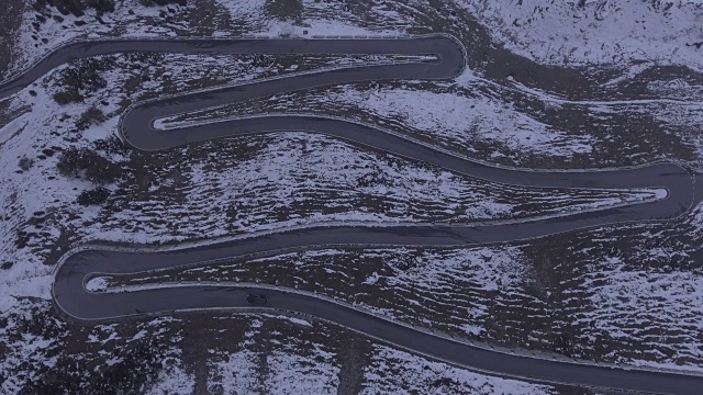 意大利斯特尔维奥隘口，汽车在雪山中蜿蜒行驶的鸟瞰图视频下载