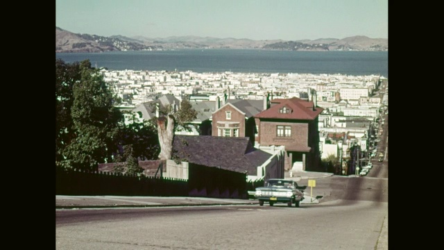 1959年雪佛兰黑斑羚汽车行驶在陡峭的山路上，背景是城市/美国加州旧金山视频素材