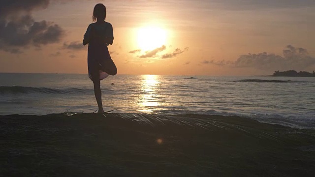 在海滩上做瑜伽。女人沉思在树的姿势。日落视频素材